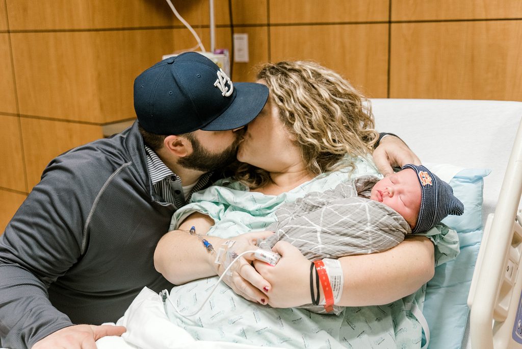 Parents kissing while holding newborn baby