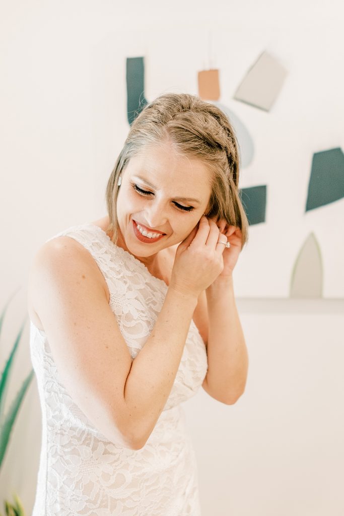 Bride smiling putting earring in