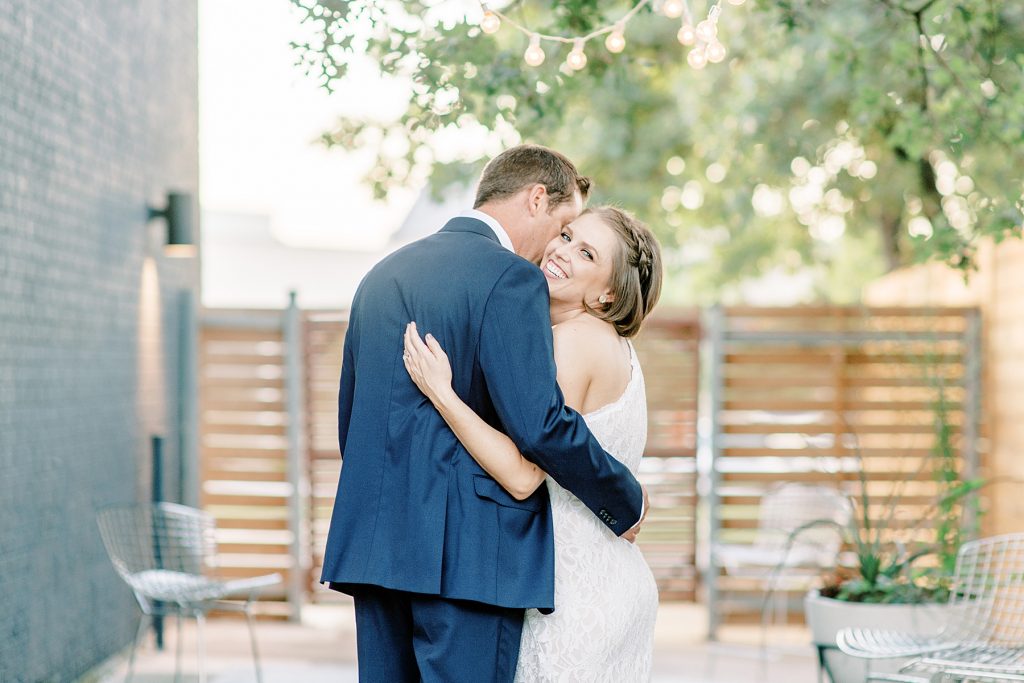 Bride looks over shoulder laughing while groom kisses her