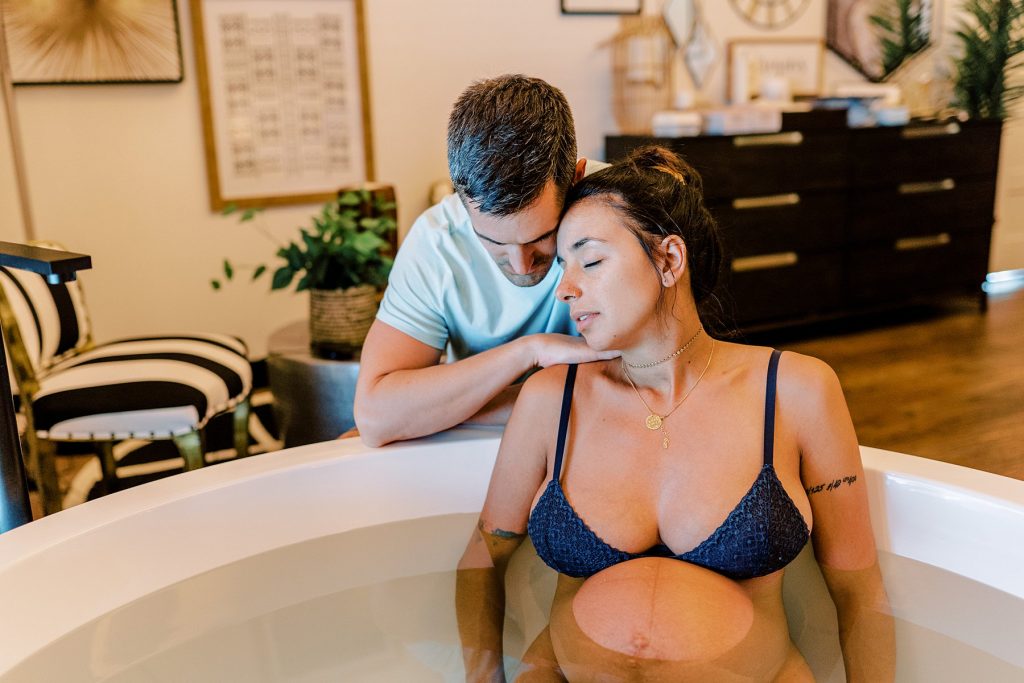 Pregnant woman sitting in bath to help with labor