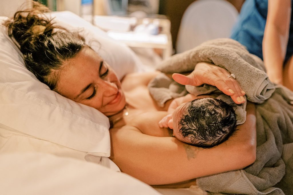 Mother holding her newborn in bed after an Origins water birth 