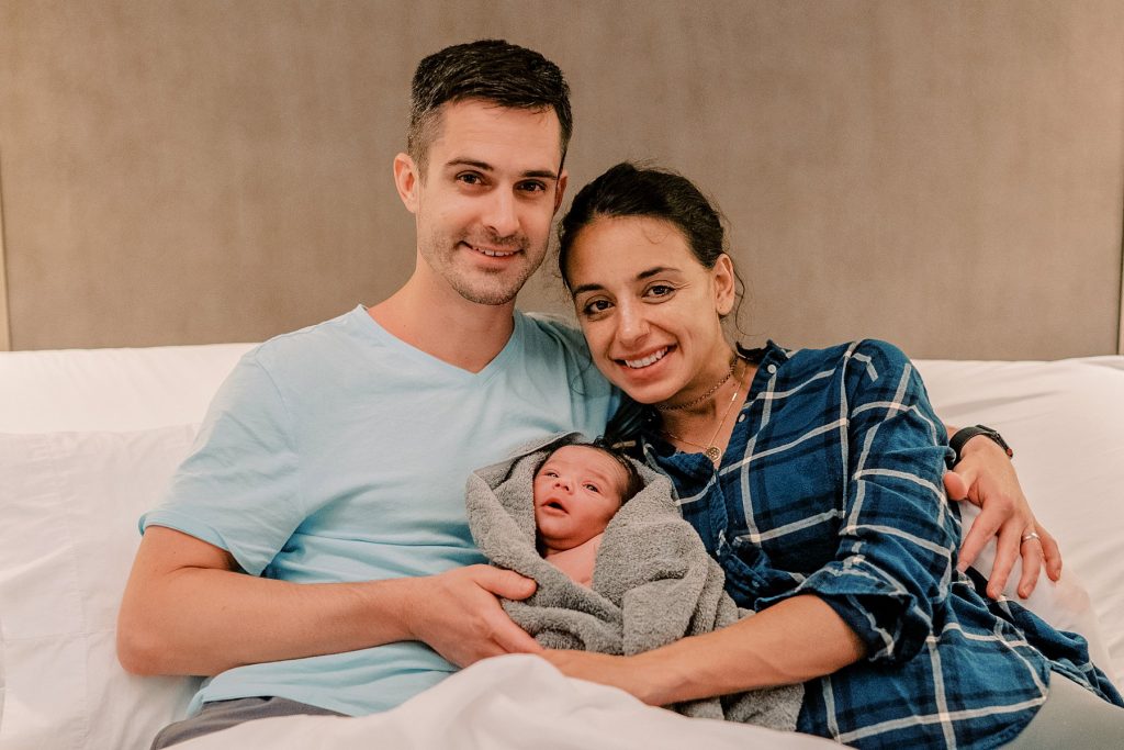 Couple leaning together cuddling their newborn baby
