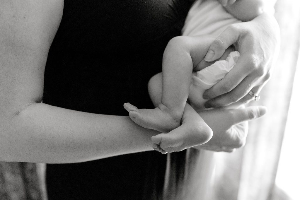 BW of mother holding newborn baby showing baby feet