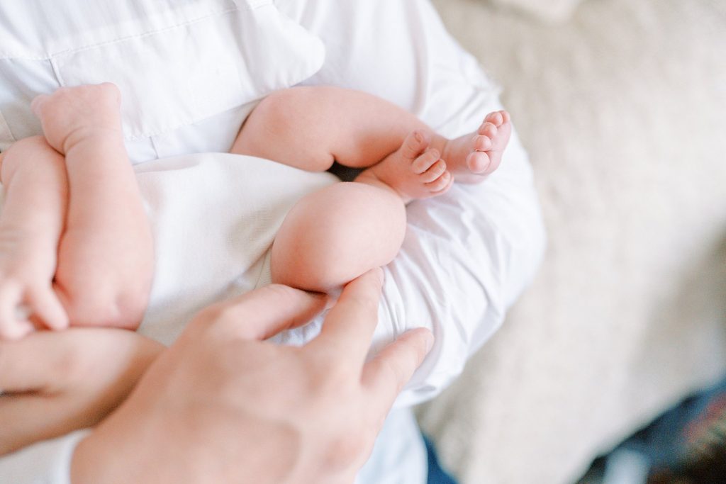 Father holding newborn exposing baby feet