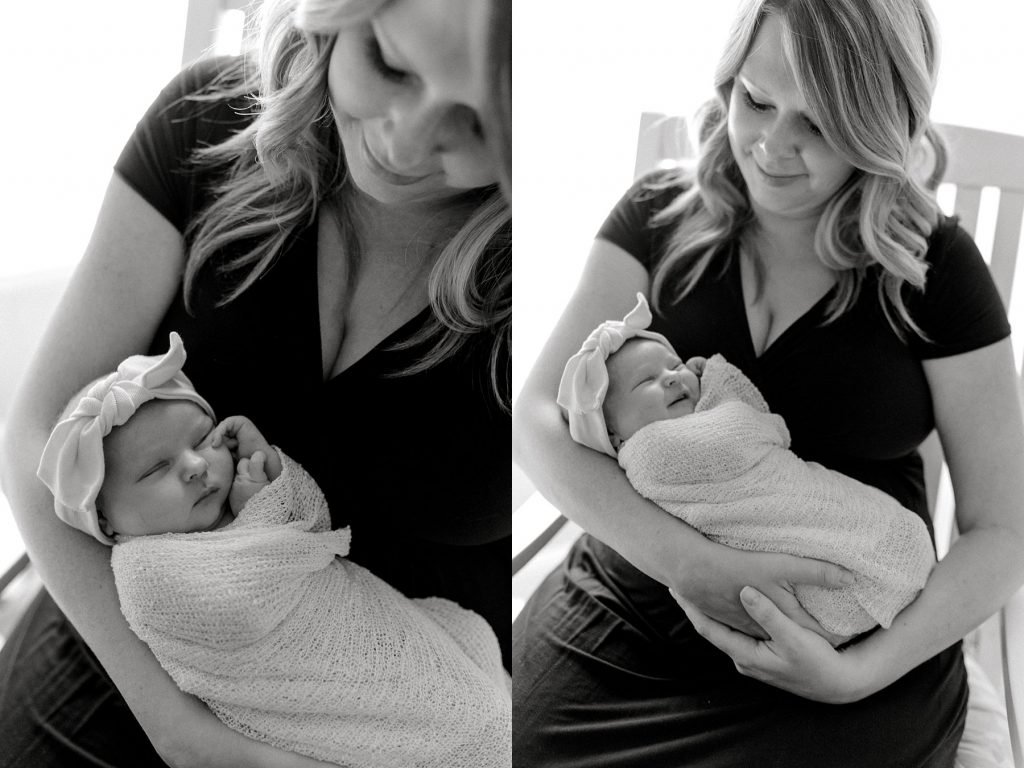 BW mother holding baby girl in rocking chair while baby grins during her lifestyle newborn session 