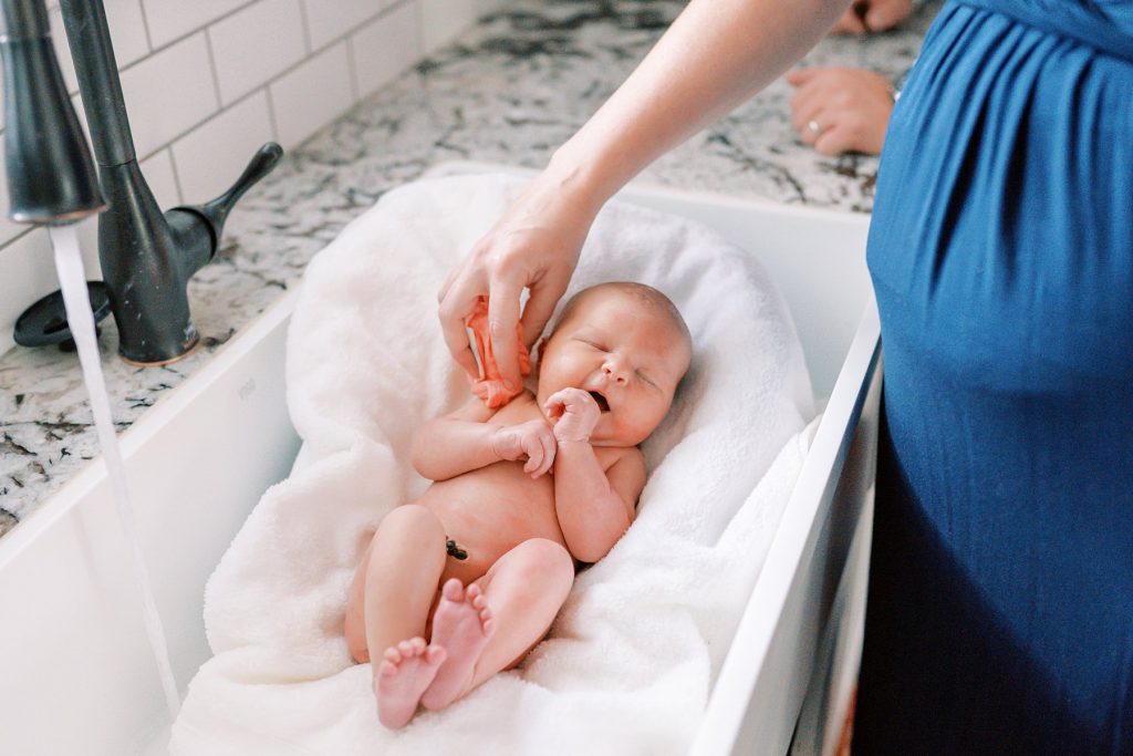 Baby yawning during sponge bath during her lifestyle newborn session 