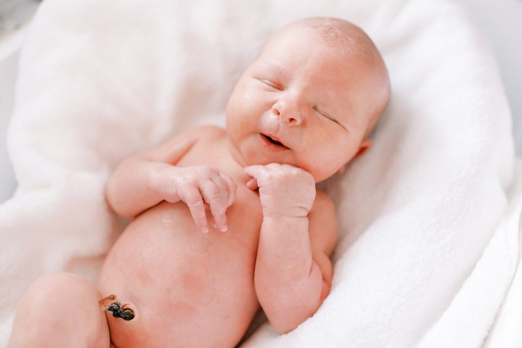 Newborn baby smiling in bath seat during her lifestyle newborn session 