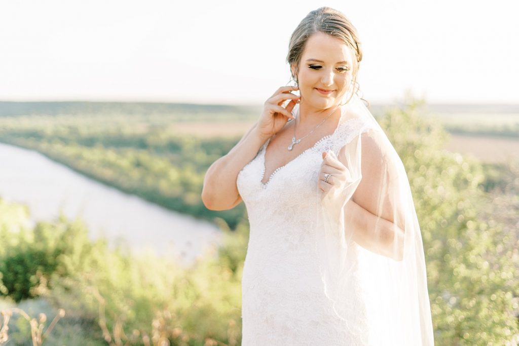 Bride looking down while touching her neck outside at Wildcatter Ranch