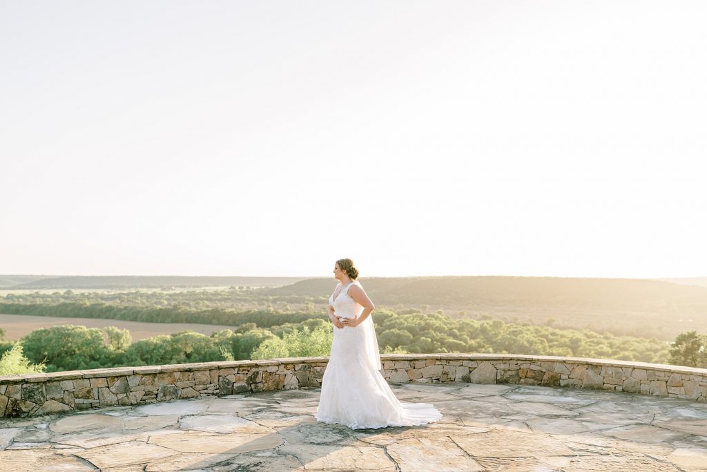 bride looking off into distance in front of landscape view at golden hour Wildcatter Ranch bridal session