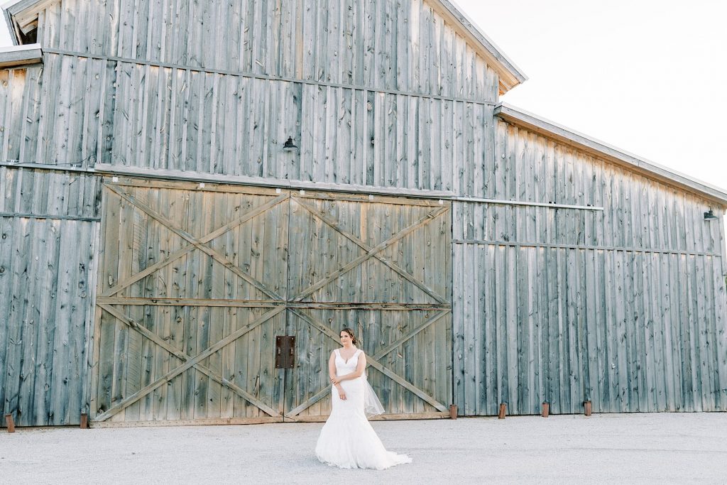 Bride standing in front of rustic barn for Wildcatter Ranch Texas bridal session