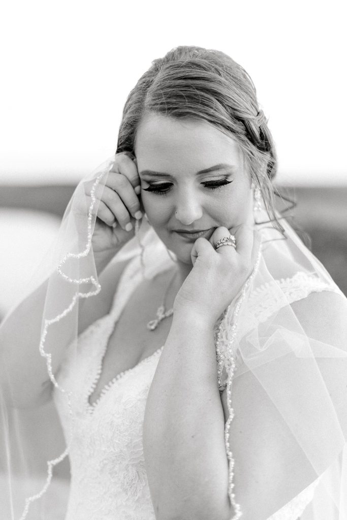 BW close up of bride holding veil up to her face