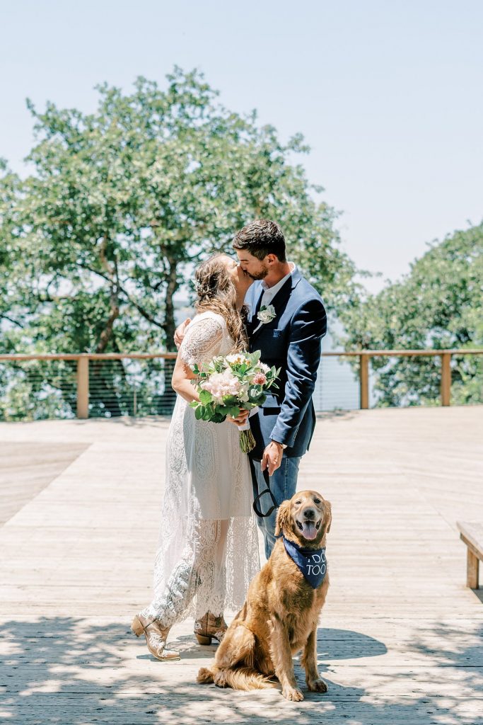 Bride and groom kiss with 'best dog' in front of them