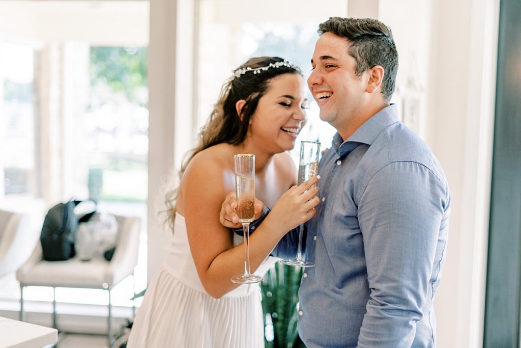 Bride and groom laughing while holding champagne glasses