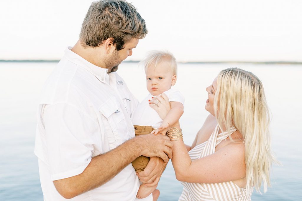 Parents holding toddler in front of lake in Murrell Park summer family session