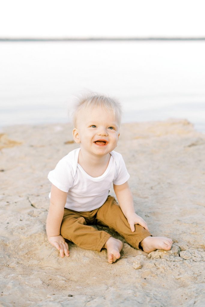 Toddler laughing on rock by lake