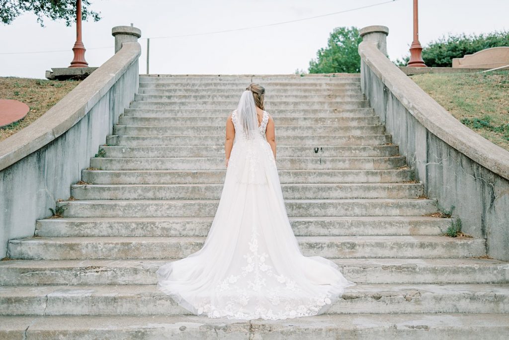 Bride standing on stairs with train running down in Fort Worth Stockyards bridal session