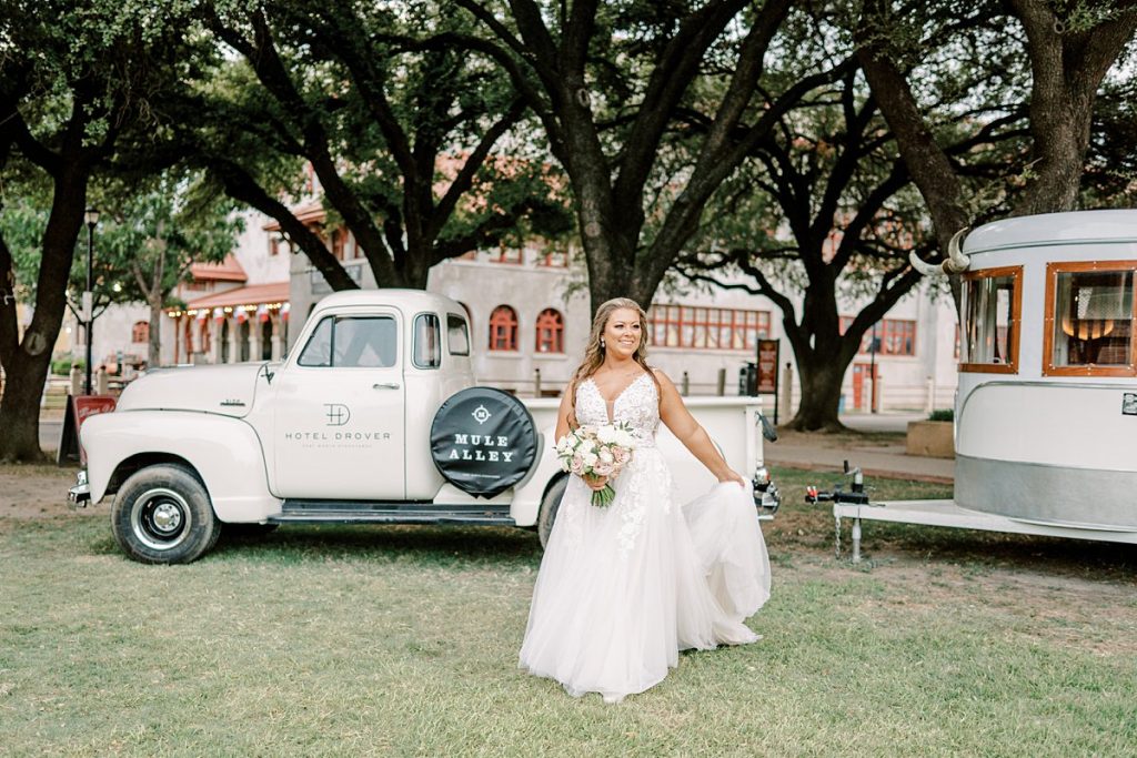 Bride walking in grass holding gown train in hand in Fort Worth Stockyards bridal session