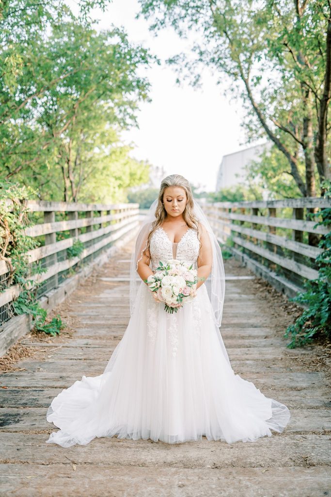 Bride holding bouquet standing on bridge in Fort Worth Stockyards bridal session