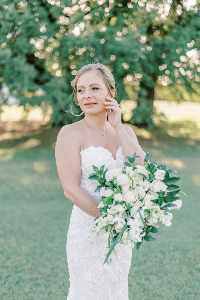 Bride holding white rose bouquet in field