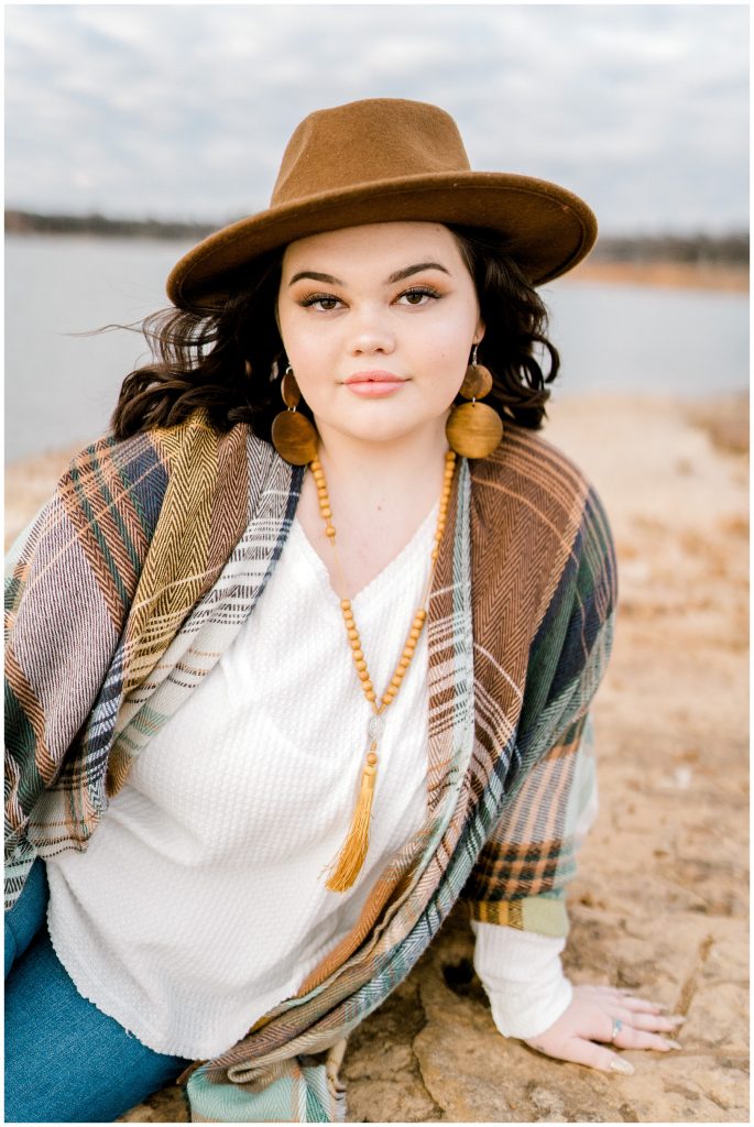 Girl sitting on rock by lake in 2020 Birdville High senior shoot