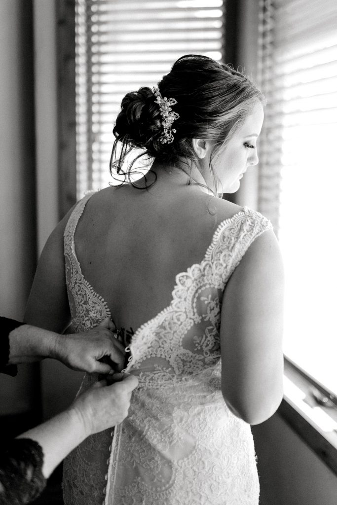 BW bride being buttoned into wedding gown
