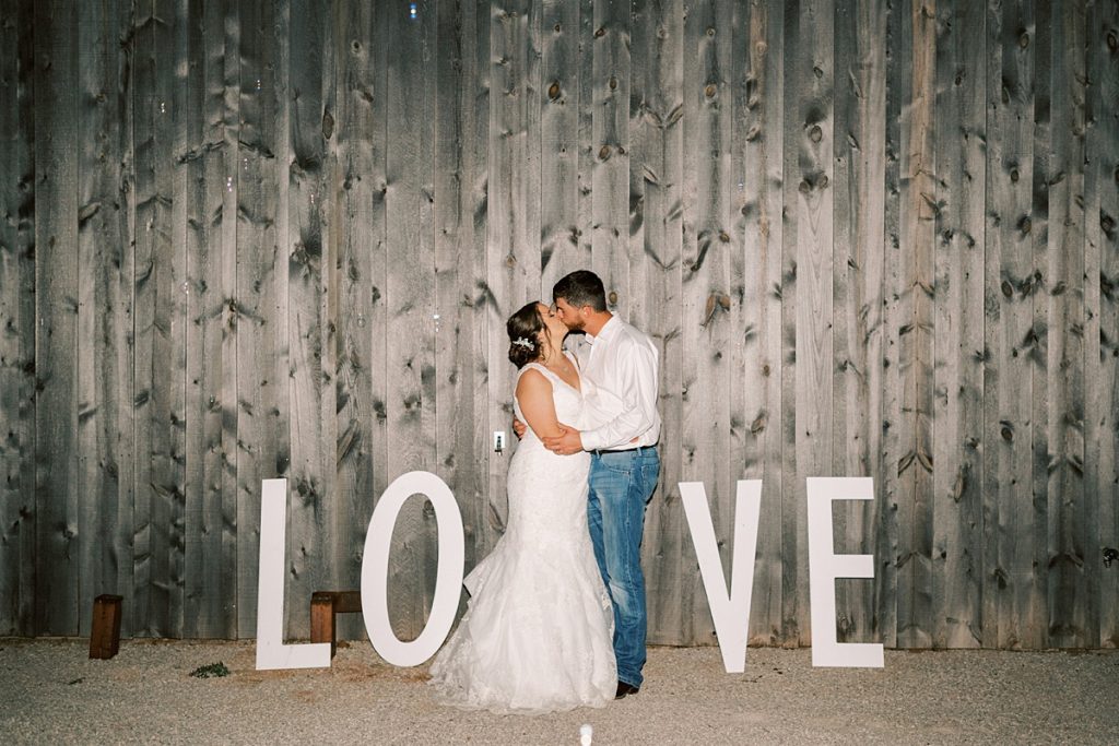 bride and groom kiss with LOVE marquee