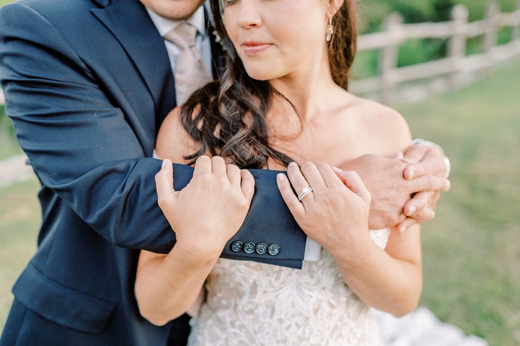 Groom arms wrapped around bride showing wedding rings