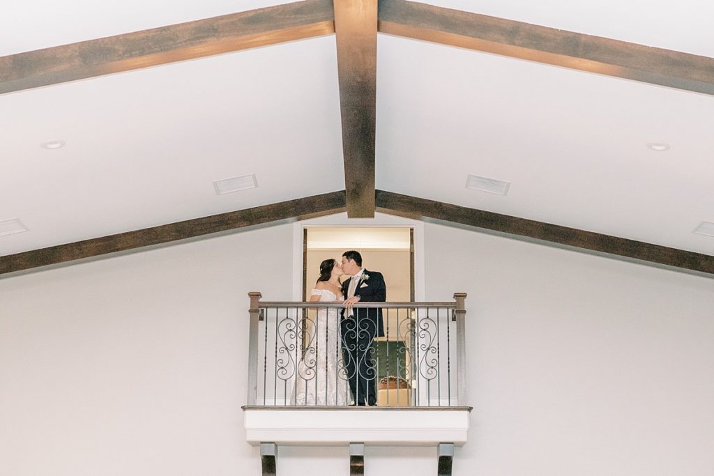 Bride and groom kiss on balcony in Dove Ridge Vineyard wedding