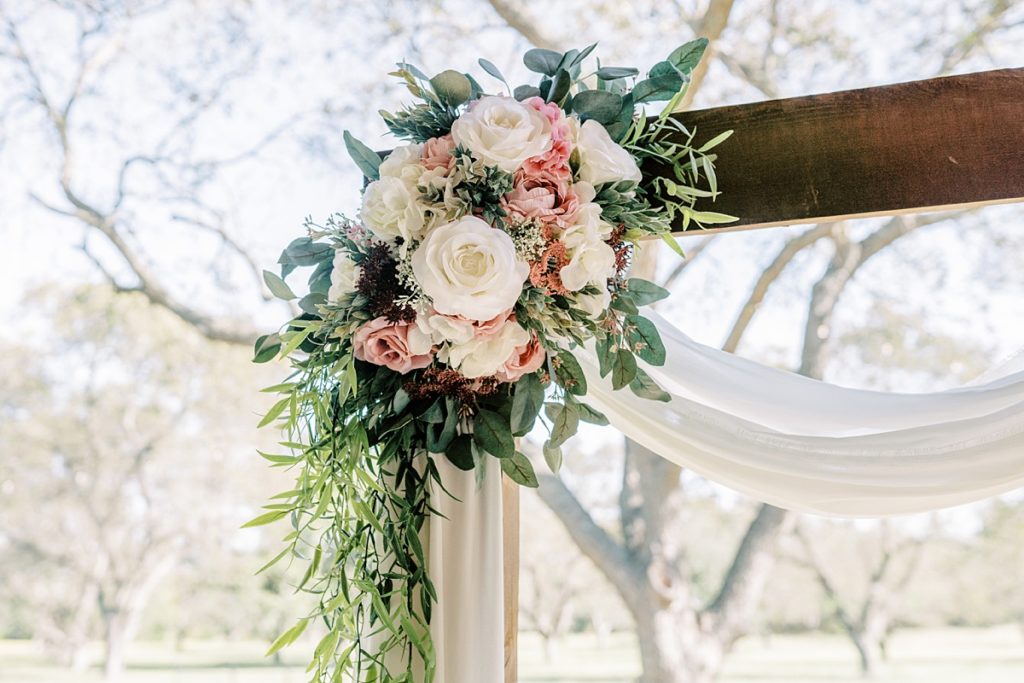 wooden wedding arch with flowers at corner