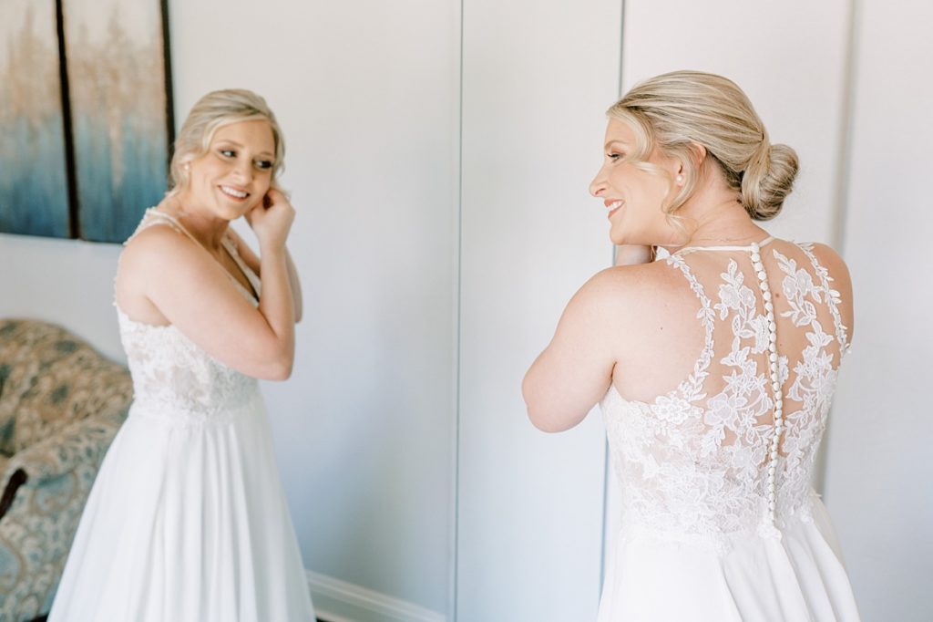 bride putting on earring in mirror