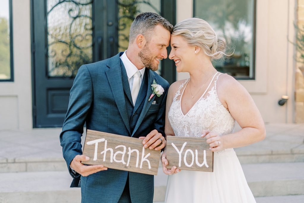 bride and groom nuzzling and holding thank you sign