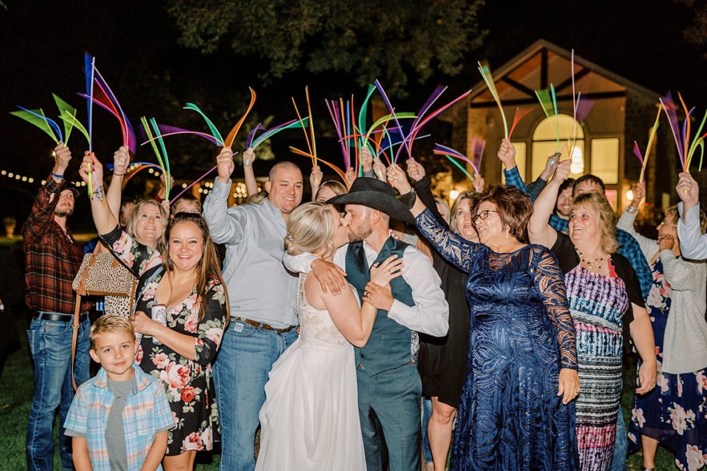 couple kissing during glow stick wedding exit