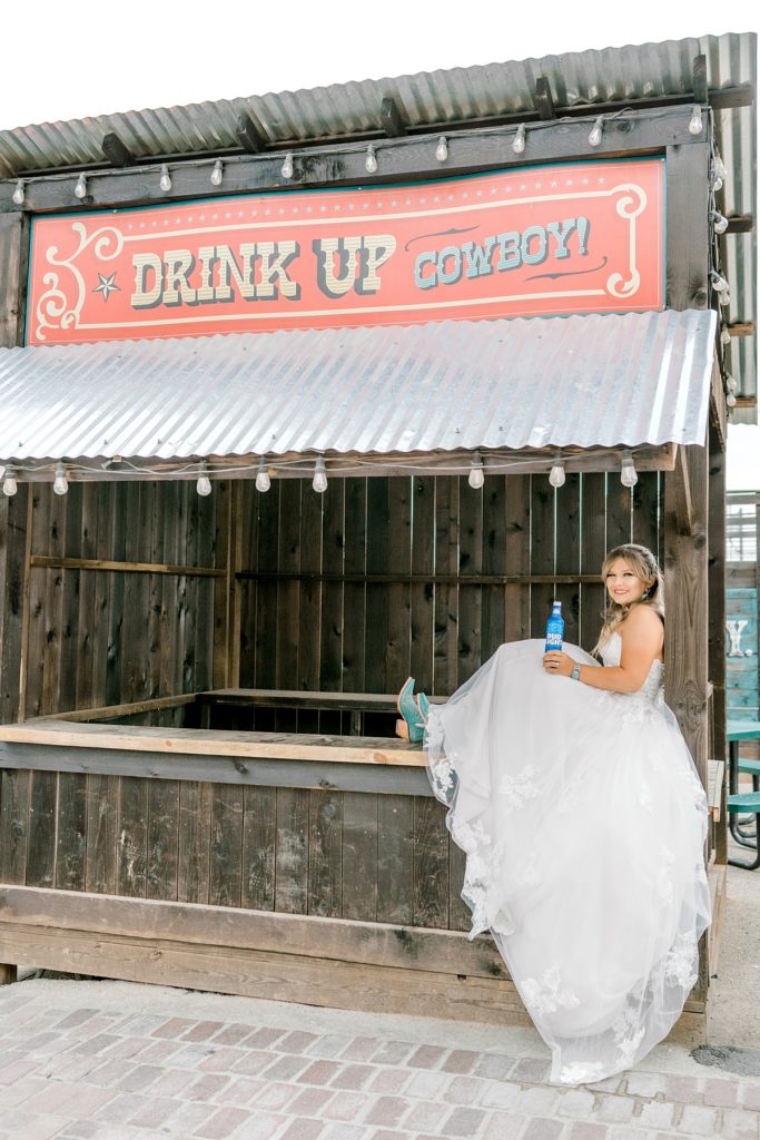 Bride sitting on booth drinking a beer in Fort Worth Stockyards Bridal session