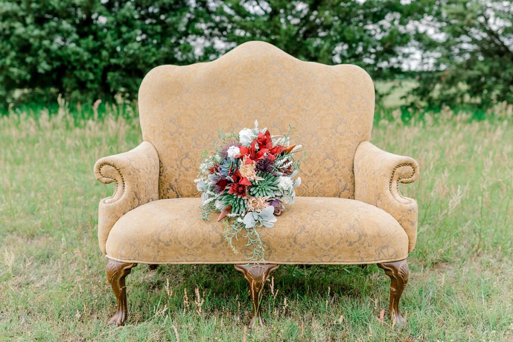 red wildflower wedding bouquet sitting on gold vintage chair