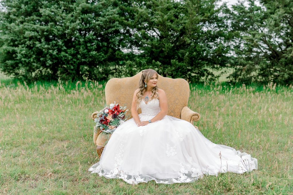 Bride sitting on gold vintage chair in field