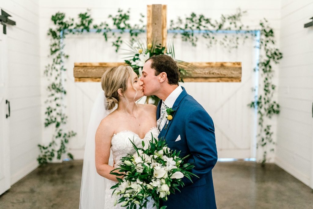 Bride and groom kiss at alter Five Oaks Farm