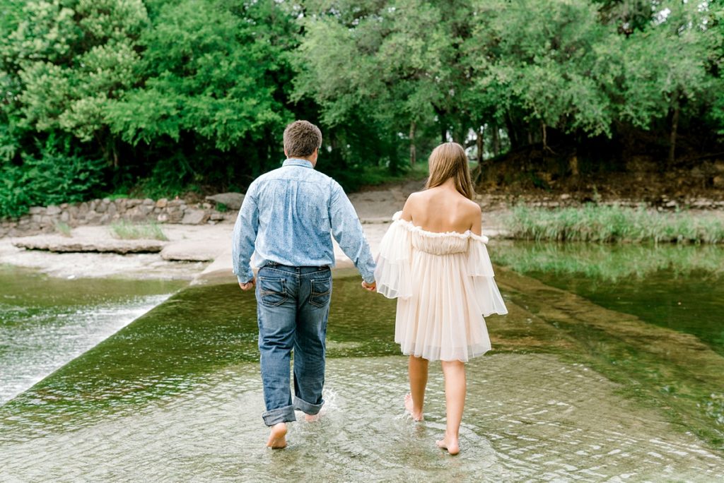 couple holding hands walking through water