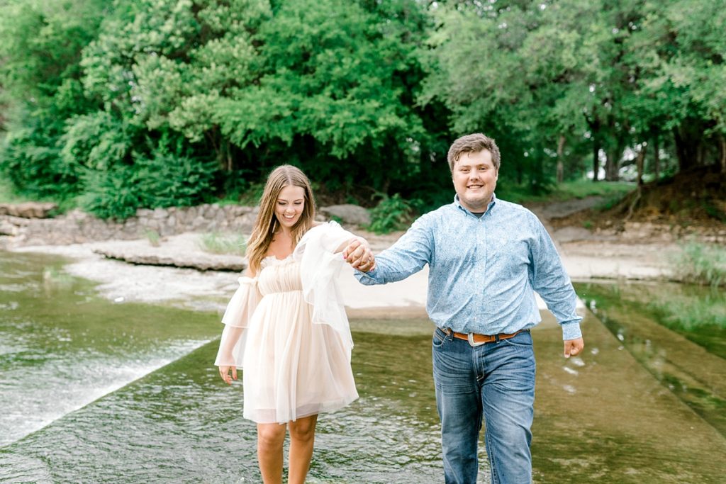 couple laughing and playing in waterfall engagement