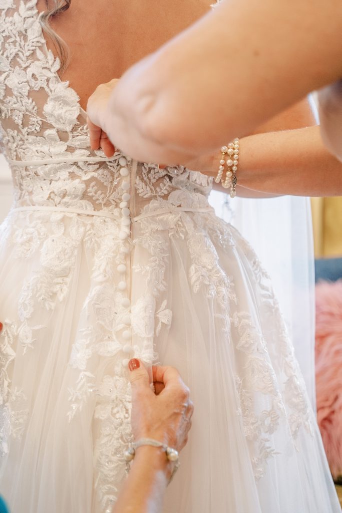 bride being buttoned into wedding gown