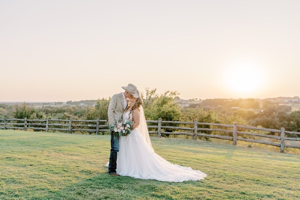 bride and groom kissing on grass at Diamond H3 ranch wedding venue