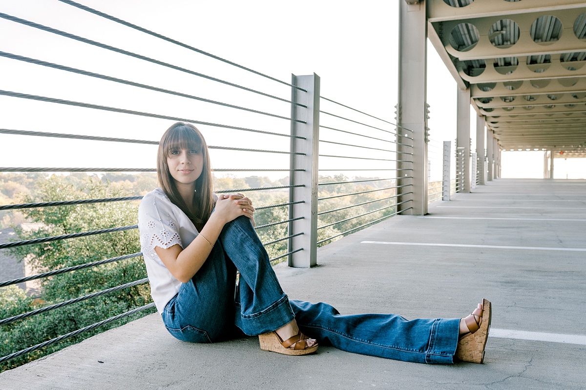girl sitting against railing in parking garage