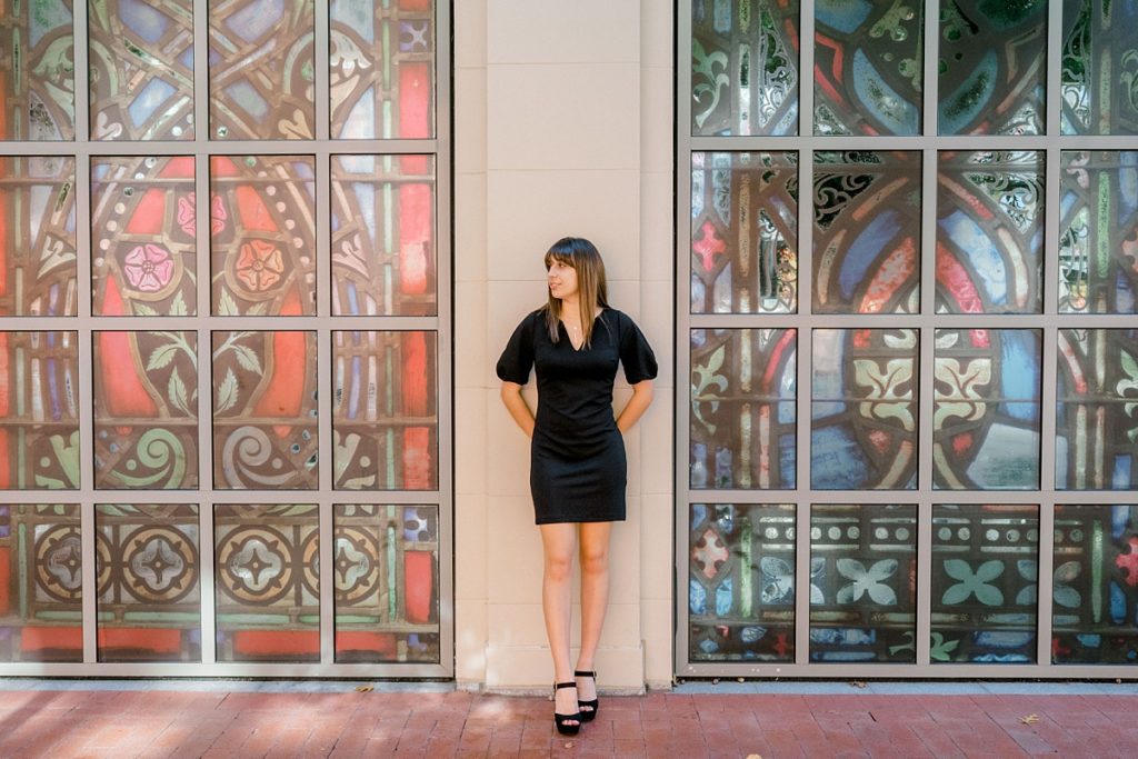 Girl standing against wall between stained glass windows Texas senior session