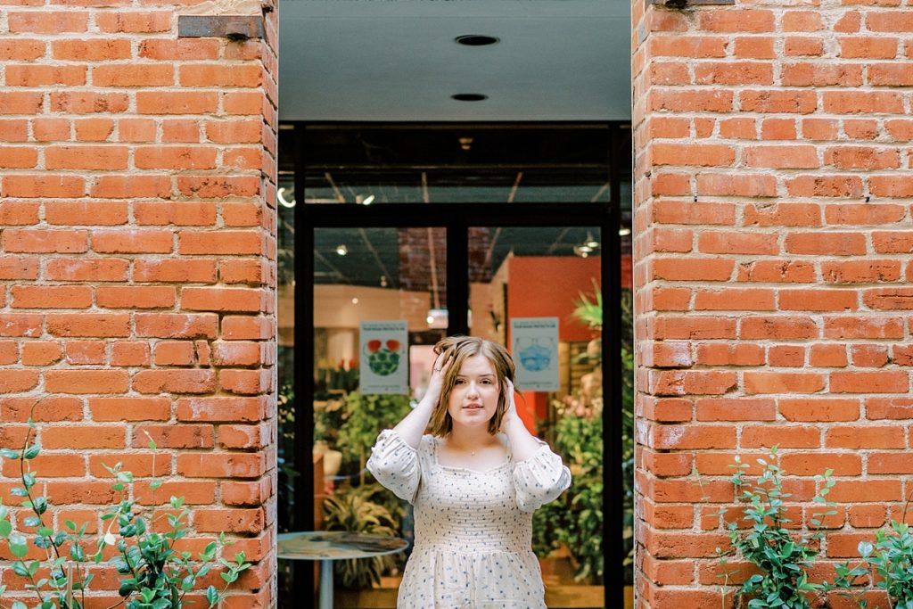 girl standing between brick entry in 2021 high school senior session