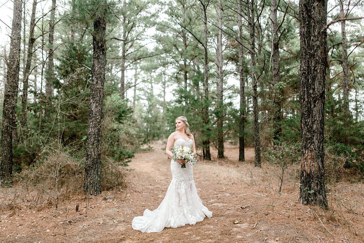 Bride standing in woods holding bouquet in outdoor bridal session Texas