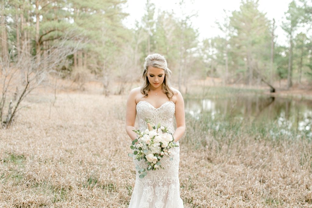 bride standing in front of pond in woods for Texas bridal session