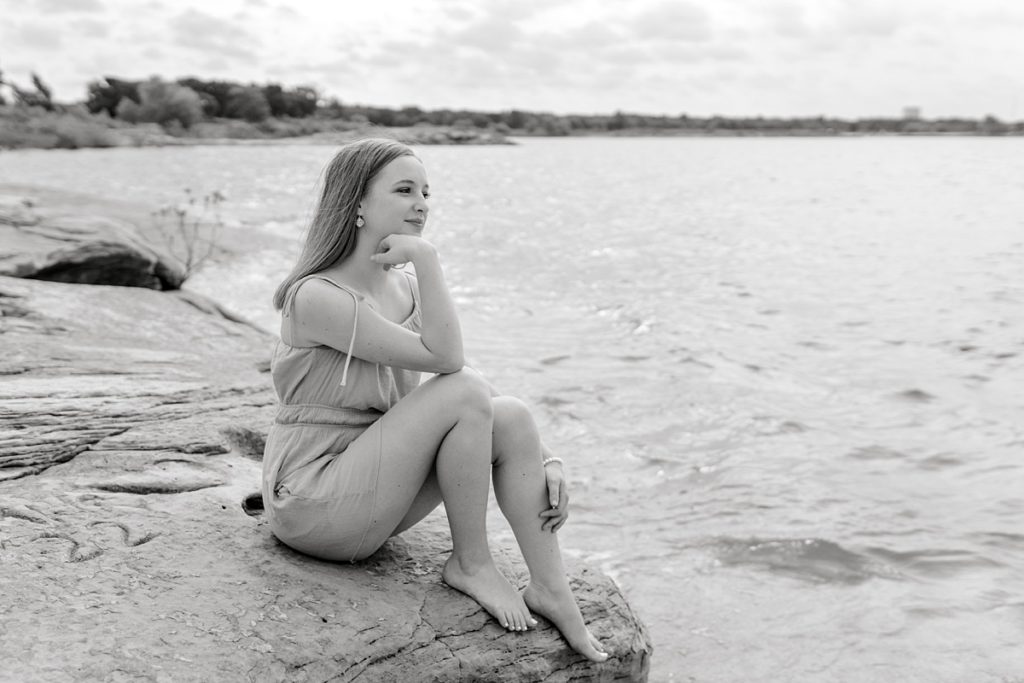 Girl sitting on rock by lake in Fort Worth Texas senior session