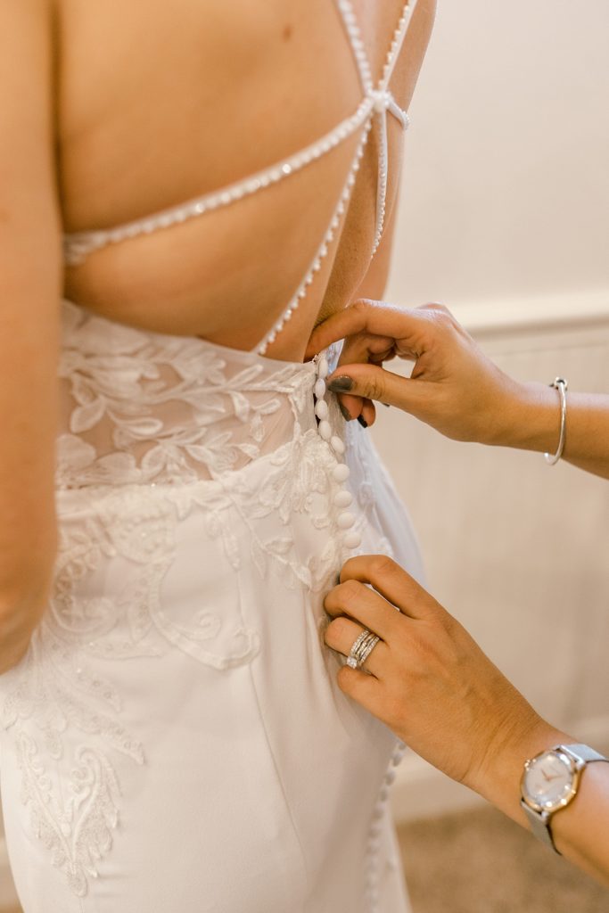 bride being buttoned into gown