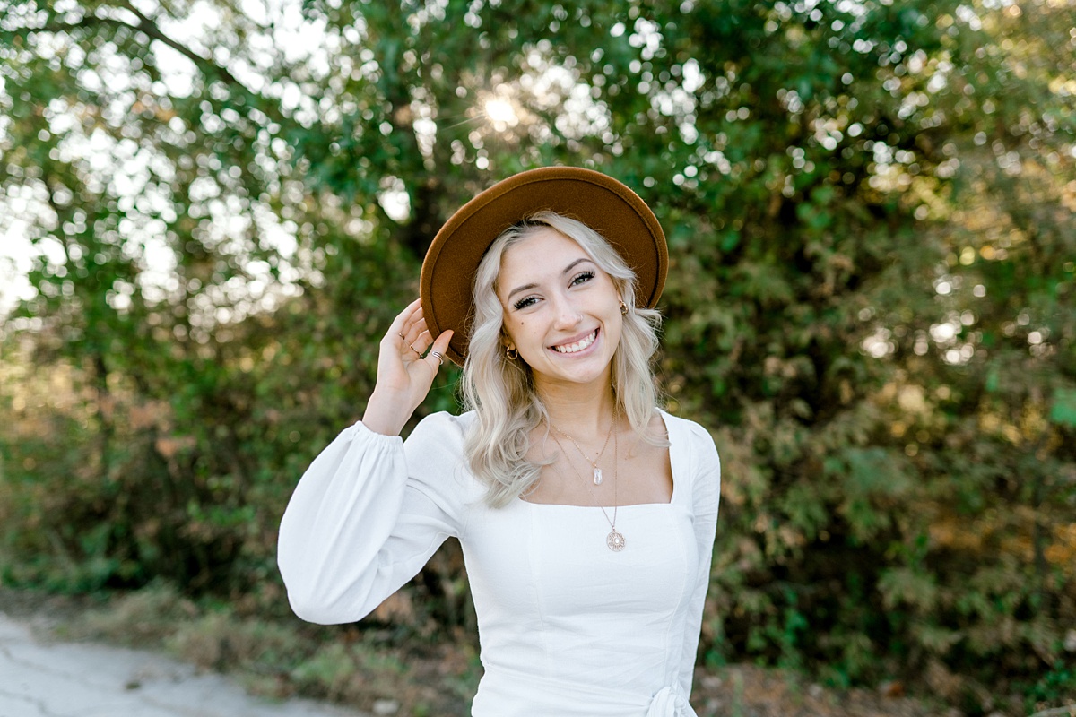 girl standing in white dress with brown hat Texas senior session