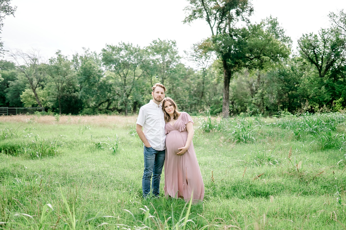 couple standing in field for maternity photos