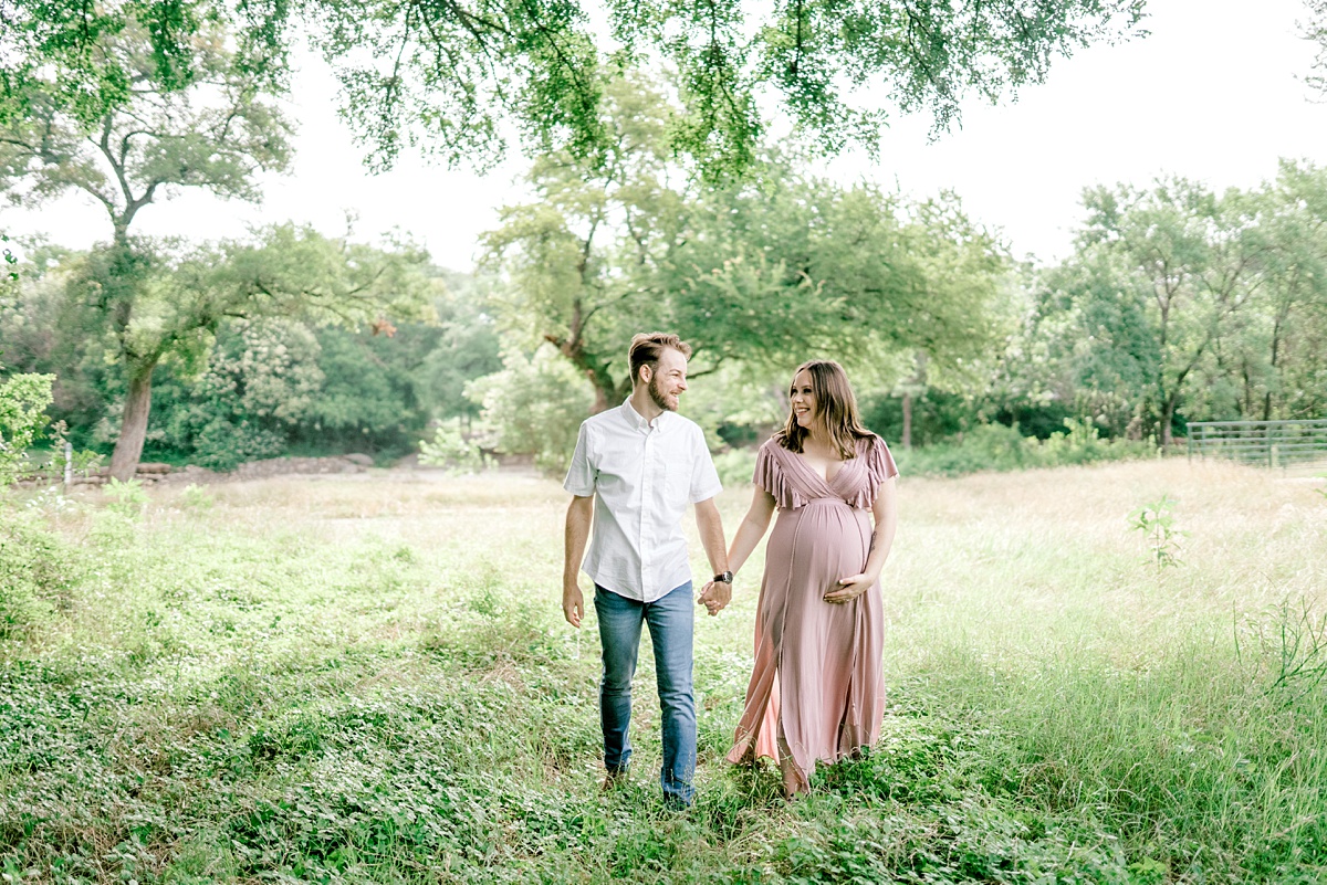 pregnant couple holding hands in field for Texas maternity session